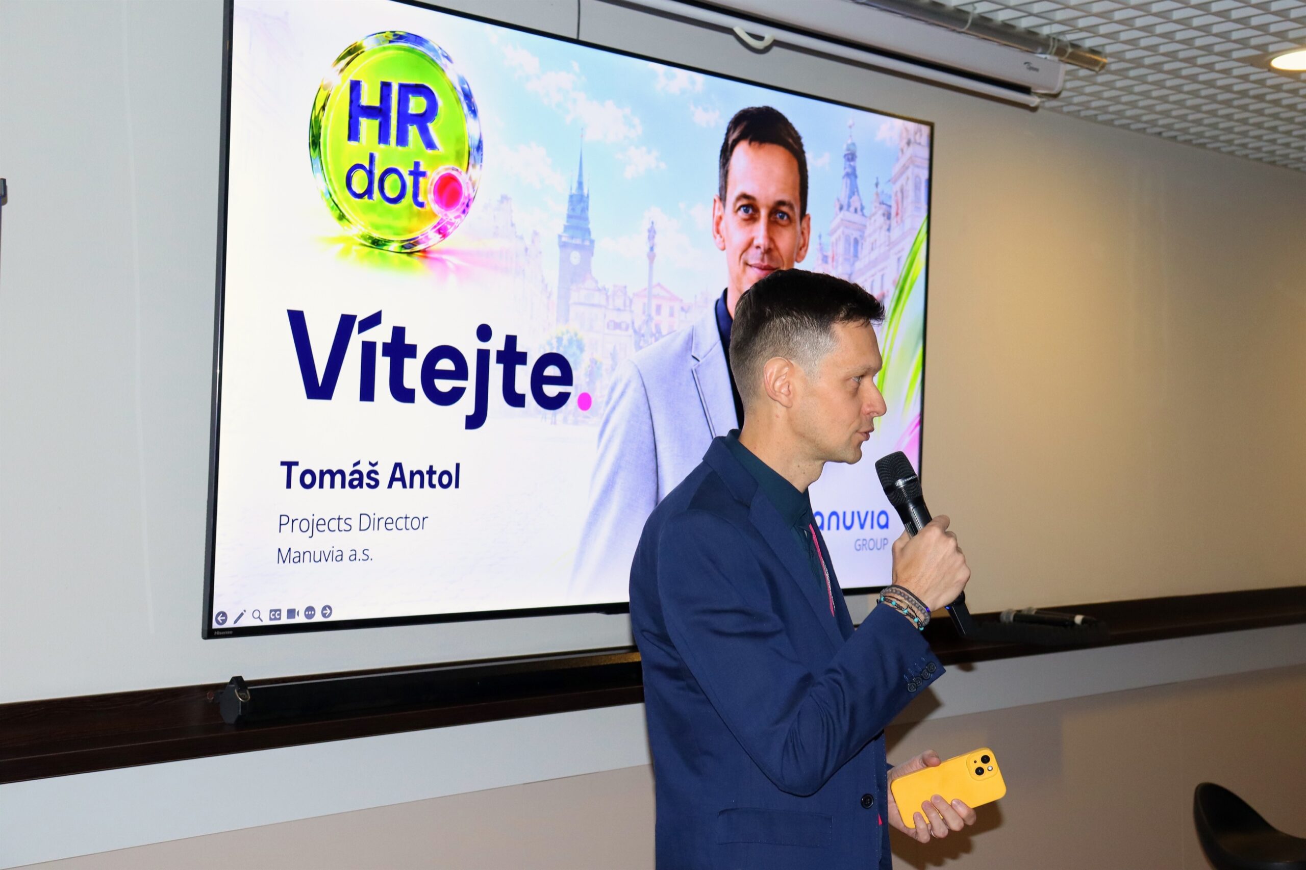 Tomáš Antol s mikrofonem před uvítací obrazovkou HRdot